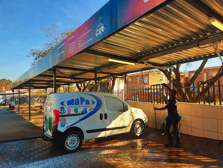 An operator washing a van at a real commercial wash bay